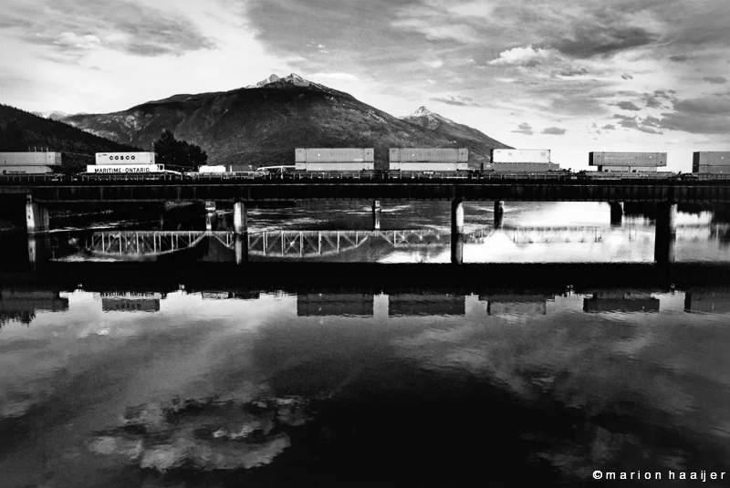 Een trein en bergen weerspiegelen in stil water